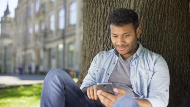 Estudiante universitario comprobando información sobre el teléfono celular, resultados exitosos, feliz — Vídeo de stock