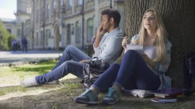 Cep telefonu ağaç altında not defterinde notlar alarak kız konuşurken çok ırklı adam