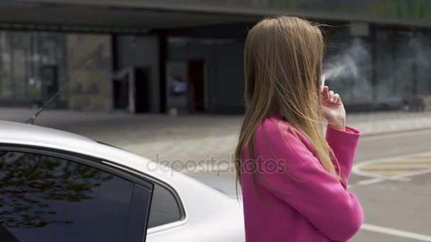 Hosszú hajú nő áll közel autó és a dohányzás egyedül, barátja vár — Stock videók