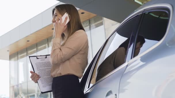 Lady broker szerződés beszél ügyfél okostelefon, állandó közelében autó — Stock videók