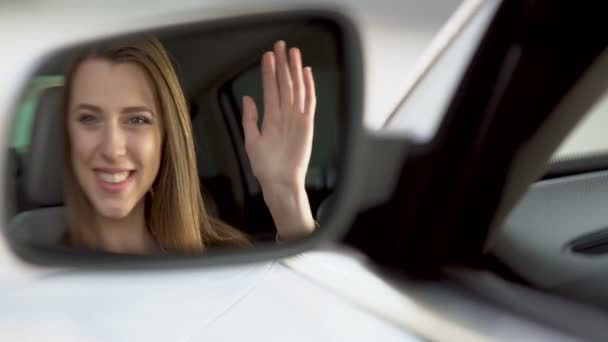 Женщина-знаменитость сидит в автомобиле и машет рукой, зеркало заднего вида отражение — стоковое видео
