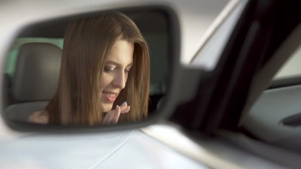 Young joyful woman sitting in car and scrolling on tablet or smartphone, mirror — Stock Video