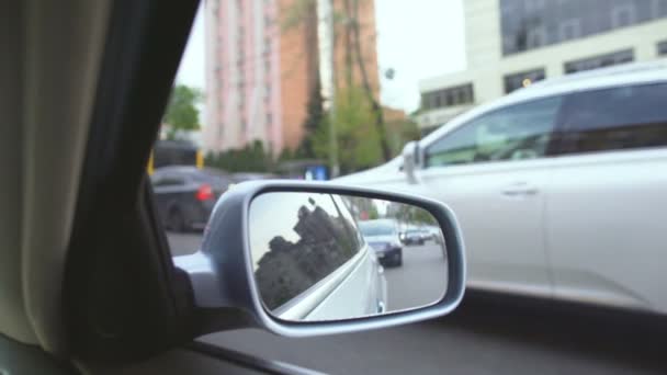Vista da auto in movimento, riflessione nello specchio retrovisore. Blocco del traffico in città — Video Stock
