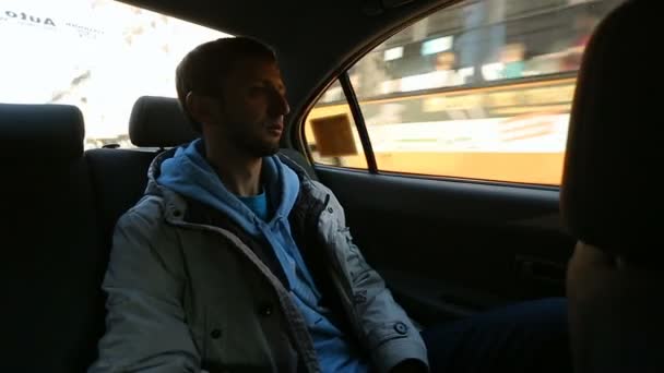 Uomo seduto sul sedile posteriore della macchina, guardando fuori dal finestrino le strade, corsa in taxi — Video Stock