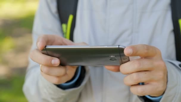 Junger Mann hält und tippt Handy in den Händen, benutzt Anwendung, Suche — Stockvideo