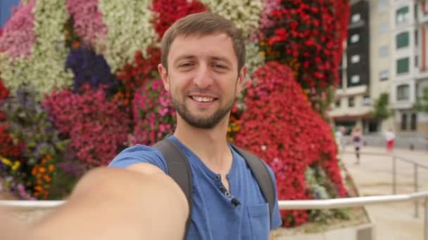 Hombre sonriendo y tomando selfie video cerca de la escultura floral, diversión con la cámara — Vídeo de stock