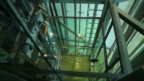 Lift moving upwards and arriving on the floor, view through glass elevator shaft — Stock Video
