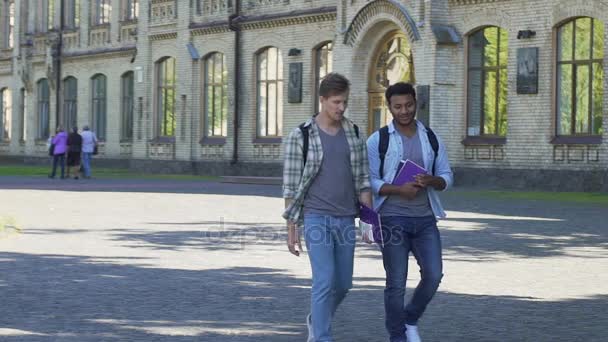 Los mejores amigos masculinos caminando cerca de la academia y hablando entre sí. Estudiantes — Vídeos de Stock