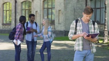 İnek yalnız erkek ayakta ve kompozisyon, grup çok ırklı arkadaşıyla konuşurken okuma