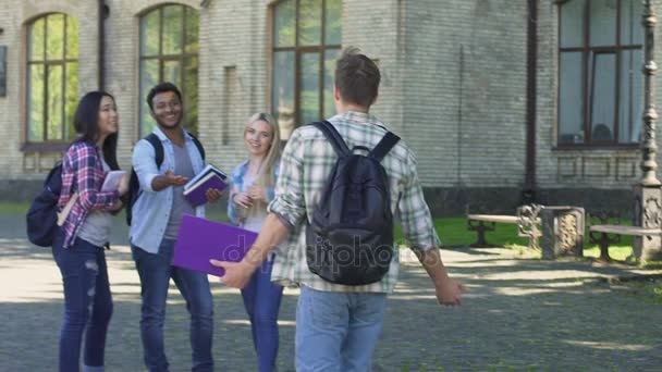 Estudiante caminando a los mejores amigos que lo esperan cerca de la universidad, estudiantes abrazándose — Vídeo de stock