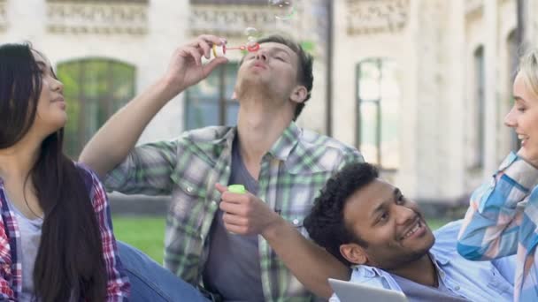 Grupo multi-étnico de amigos relaxando perto da faculdade e soprando bolhas, slow-mo — Vídeo de Stock