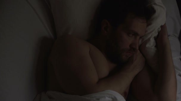 Homme bouleversé avec l'impuissance couché dans le lit et ne peut pas dormir, penser à des problèmes — Video