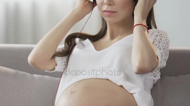 Esperando fêmea colocando fones de ouvido, escolhendo música do telefone celular, melodia — Vídeo de Stock