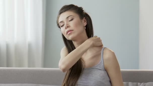 Молодая женщина массирует шею и плечи, снимая тревожную боль, жесткую шею — стоковое видео