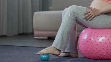 Fitness topu üzerinde oturan Anne lastik top, vücut bakımı ile ayak Masaj