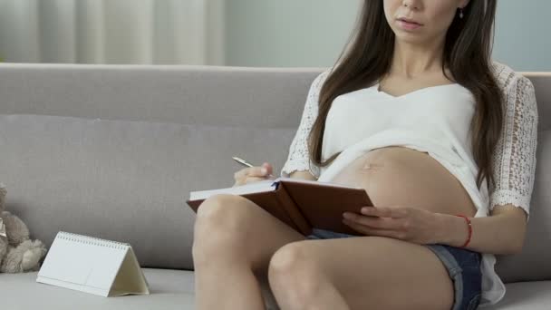 Mulher grávida sentada com caderno e calendário contando dias, matemática gravidez — Vídeo de Stock