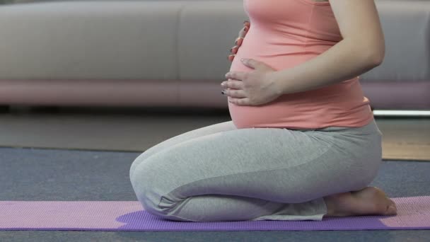 Calmo mãe-a-ser ajoelhado no chão e tocando barriga, gravidez exercício — Vídeo de Stock