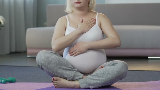 Gelecekte anne yere, oturma ovuşturarak onun mide, cross-legged poz, yoga — Stok video