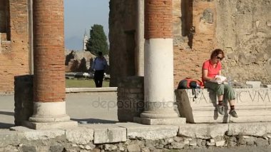 Naples, İtalya - Temmuz 2014 yaklaşık: Gezi şehrin. Baştaban sütun, Meydanı'nda yürüyüş turist ile oturan kadın