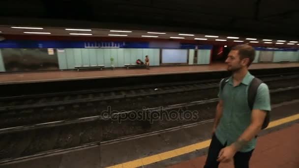 Un tipo parado en una plataforma vacía en el metro y esperando a que llegue un tren. — Vídeo de stock