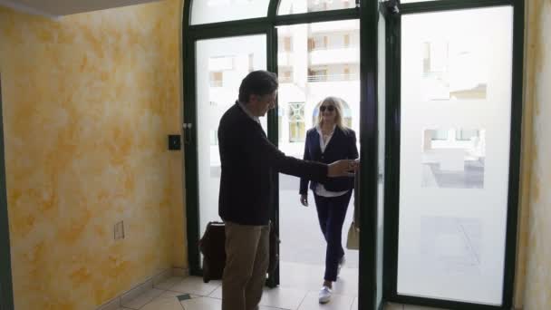 Пожилая супружеская пара, въезжающая в многоэтажное здание, чтобы посмотреть квартиру в аренду — стоковое видео