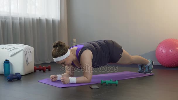 Tjej att göra stora ansträngningar för att stå i plankan position, arbetar hårt för att gå ner i vikt — Stockvideo