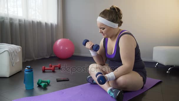Niña gorda levantando pesas para fortalecer los músculos de los brazos, haciendo ejercicios difíciles — Vídeos de Stock