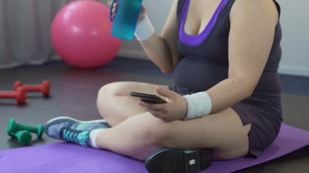 Kövér nő görgetés sport app-ra-a smartphone, figyeli a fogyás eredmények — Stock videók