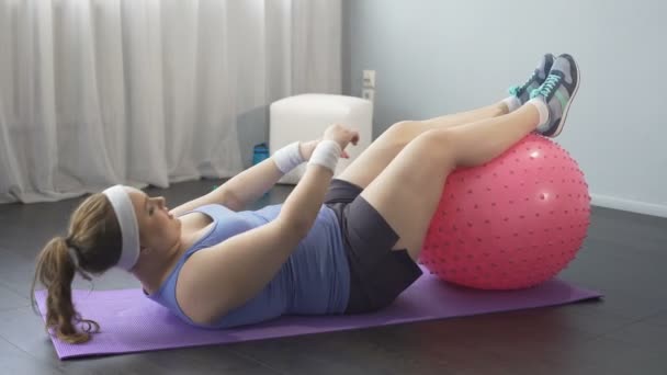 Knubbig flicka arbetar hårt för att gå ner i vikt, försöker nå fötter med händerna, träning — Stockvideo