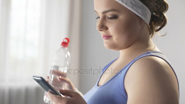 スポーツ女性スクロール彼女のスマートフォンは、体重減少の新しい方法を探して — ストック動画