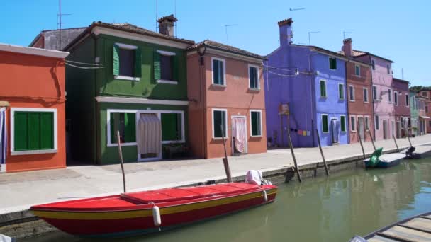 Boote in der Nähe der Seebrücke in Burano geparkt, Blick auf puppenartige bunte Häuser, Venedig — Stockvideo