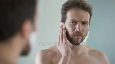 Orta yaşlı sakallı adam traş köpüğü uygulama yüz, sabah ritüeli, ayna