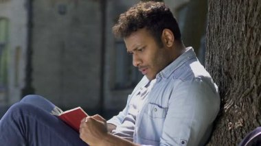 Genç erkek romantik kafa ile kitap okuma basılı kelime, dünyanın içine daldı