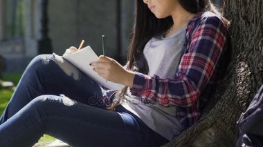 Kız öğrenci Sanatlar Fakültesi çizim, kampüste ağacın altında oturup ilham