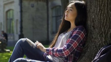 Karışık ırk kız sıcak güneş ışınlarının ağacın altında oturan ilham arıyorum