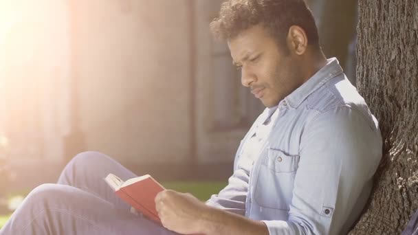 Biracial chico cuidadosamente la lectura de libro con impaciencia tragar y repensar cada palabra — Vídeos de Stock