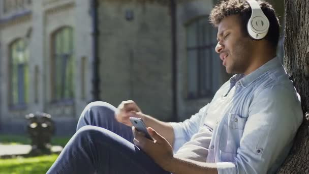 Biracial chico escuchando la estación de radio favorita disfrutando de sonido en los auriculares — Vídeo de stock