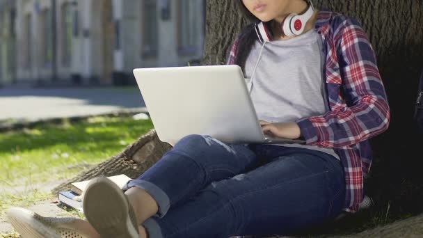 Blandad ras student gör hennes examensarbete som sitter med laptop openair — Stockvideo