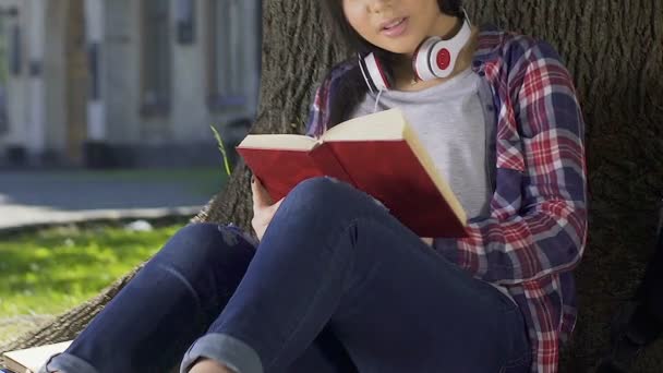 Estudiante leyendo libro tomado de la biblioteca universitaria, haciendo su tarea — Vídeo de stock