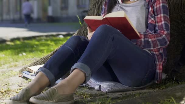Леди читает романтический роман в парке, беспокоится о героях книг, бестселлер — стоковое видео