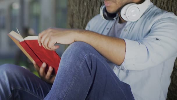 Νεαρός άνδρας διαβάζοντας το βιβλίο αυτοβελτίωσης σε εξωτερικούς χώρους, εκπαίδευση για τη μελλοντική επιτυχία — Αρχείο Βίντεο