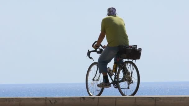 वरिष्ठ माणूस सायकलिंग आणि समुद्र आश्चर्यकारक दृश्य आनंद, छान तटबंदी, हळू-मो — स्टॉक व्हिडिओ