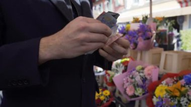 Çiçek buketi dükkanında ayakta ve cüzdanında para sayma işadamı