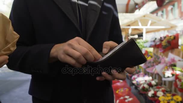 Rich man giving money to poor beggar loitering at flower market asking for alms — Stock Video