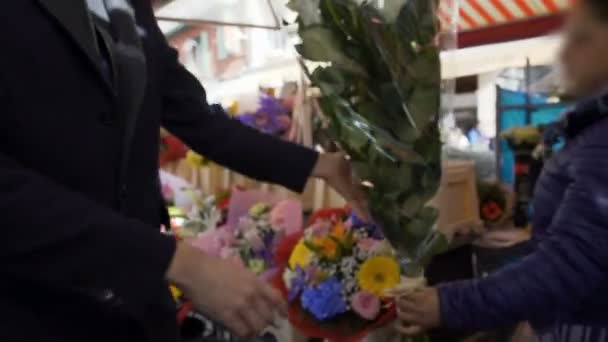 Елегантний чоловік купує величезний букет квітів, поспішаючи на побачення з коханою — стокове відео
