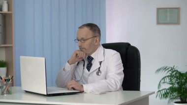 Baş hekim klinik ofisinde hastaların tıbbi kayıtları dikkatle okuyan