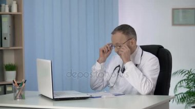 Erkek doktor hastaların, zor iş günü sonra yorgun tıbbi kayıtları görüntüleme