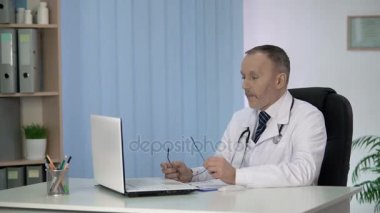 Yorgun erkek terapist laptop, elektronik tıbbi kayıtları doldurma çalışma