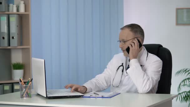 Лікар загальної практики, що надає онлайн та телефонні консультації, обслуговує пацієнтів — стокове відео