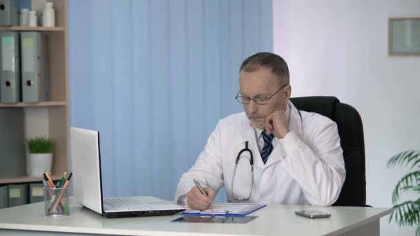 Médico llenando la historia clínica, considerando el diagnóstico y la asignación de tratamiento — Vídeos de Stock
